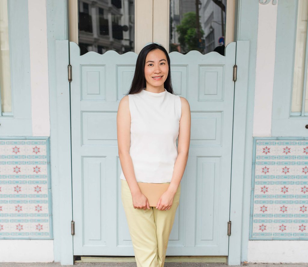 Founder Leanne Wong standing in front of a light blue gate, smiling